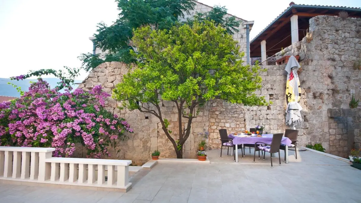 Garden at California Apartments with bougainvillea, a tree and a table on the terrace
